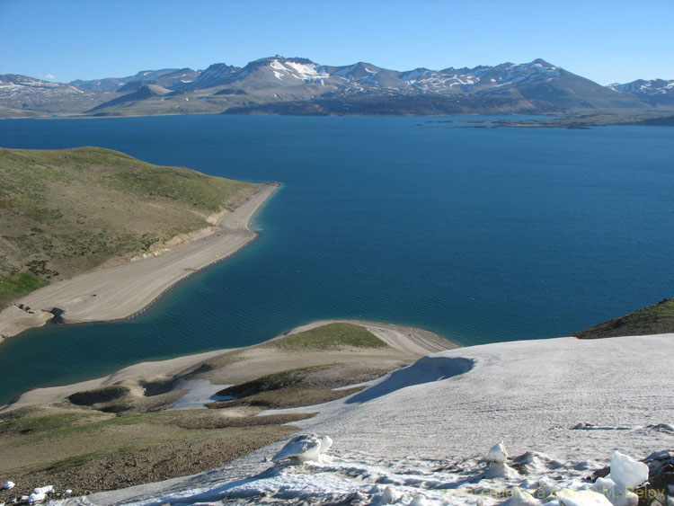 View of Laguna Maule, with some snow-covered slopes in the foreground.