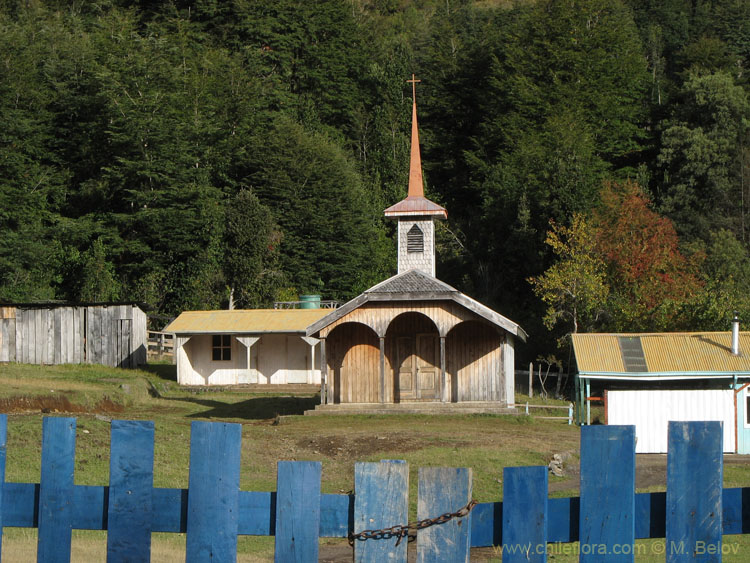 Image of a traditional wooden church behind locked wooden gate near Coaripe, Chile.