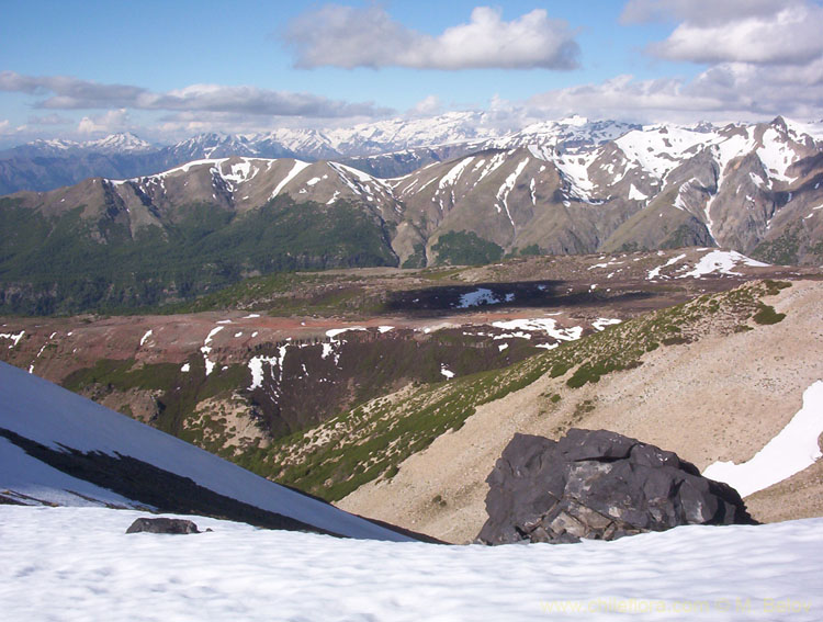 A view into a mountain valley, partially covered with snow, Radal Siete Tasas National Park.