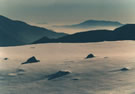 An image of a snow-covered mountain field, with large rocks, with Santiago below.