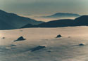 Trail to Nowhere:  An image of a snow-covered mountain field, with large rocks, with Santiago below.