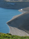 More Cosmic Geometry:  Image of volcanic ash slopes and the shore of Laguna Maule, with some green grass in foreground.