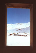 Free Painting:  An image of a wooden window frame through which an iron bridge and snow-covered mountains can be seen, in the vicinity of Ba�os Morales and Ba�os de la Colina.